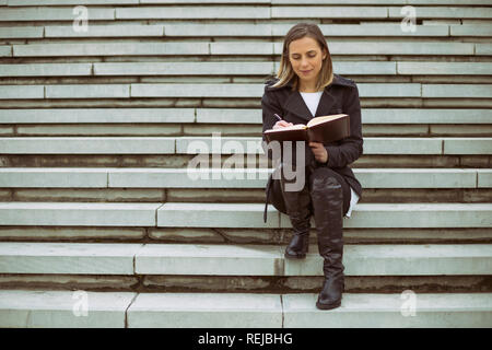Schöne Geschäftsfrau, sitzen auf der Treppe in der Stadt und arbeiten. Stockfoto