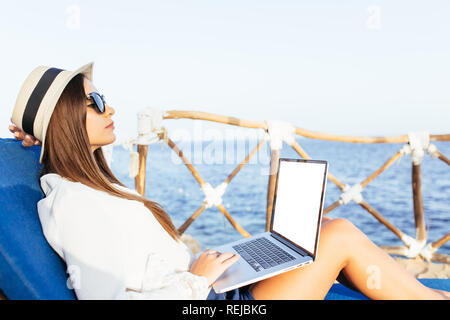 Frau arbeitet sie an ihrem Laptop am tropischen Strand. Stockfoto