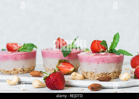 Hausgemachte raw Erdbeer Kuchen mit frischen Beeren, Minze, Muttern. Gesunde vegane Ernährung Konzept Stockfoto