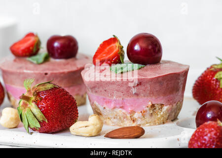 Raw Erdbeere und Kirsche Käsekuchen mit frischen Beeren, Minze, Muttern. Gesunde vegane Ernährung Konzept Stockfoto