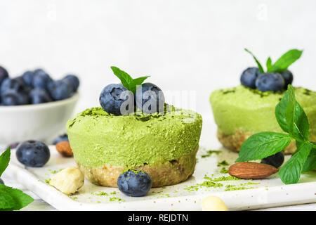 Hausgemachte raw Matcha Pulver Kuchen mit frischen Beeren, Minze, Muttern. Gesunde vegane Ernährung Konzept. Nach oben Schließen Stockfoto