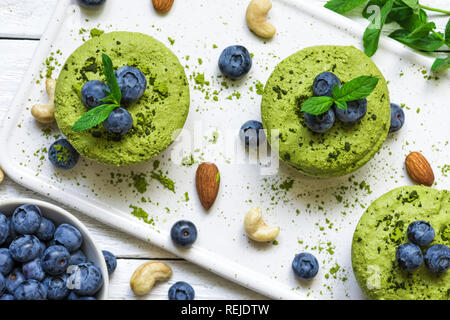 Hausgemachte raw Matcha Pulver Kuchen mit frischen Beeren, Minze, Muttern. Gesunde vegane Ernährung Konzept. top View Stockfoto