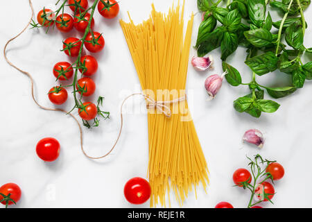 Pasta Spaghetti mit Tomaten, Knoblauch und Basilikum auf weißem Hintergrund. Zutaten für traditionelle italienische Gericht. top View Stockfoto