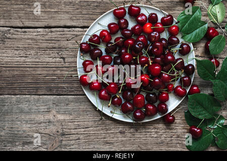 Frische Kirsche auf Platte auf rustikalen Holzmöbeln Hintergrund. frische reife Beeren. süsse Kirschen. top View Stockfoto