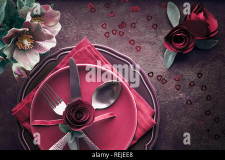 Flach mit burgindy Teller und Geschirr mit Rosen und Anemonen eingerichtet, Weihnachten oder Valentinstag Dinner Table Setup Stockfoto