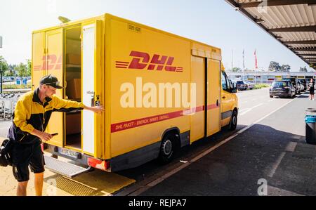 BADEN, Deutschland - 11. MAI 2018: die männlichen Kurier schließenden Tür von DHL gelben Lieferwagen nach der Lieferverzug Paket Paket Stockfoto