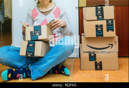PARIS, Frankreich - Jan 13, 2018: Stapel von Amazon Prime Pakete zu einem Haus Tür Frau unboxing eines der kleinen Boxen geliefert. Amazon ist der größte Internet-basierte Händler in den Vereinigten Staaten weltweit in Betrieb Stockfoto
