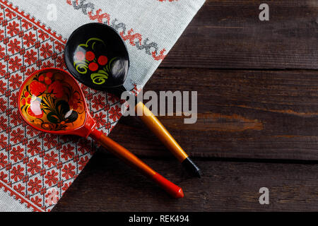 Holzlöffel mit floralen Ornament in der traditionellen Volksmusik russische Khokhloma Stil auf hölzernen Tisch mit Tischdecke mit einem traditionellen Russischen Muster. T Stockfoto