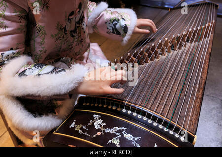 Nahaufnahme von Händen einer chinesischen Frau spielen eine Zither, einem traditionellen chinesischen Musikinstrument Stockfoto