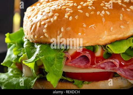 Ein Sandwich mit Salami, Käse, Tomaten und Soßen auf der Platte, Ansicht schließen Stockfoto