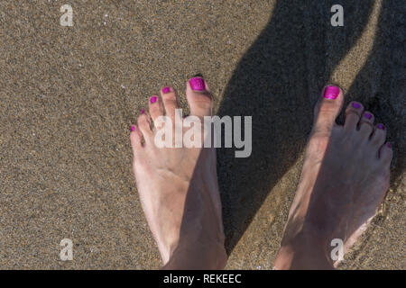 Die Füße auf dem nassen Sand während der Ferien Stockfoto