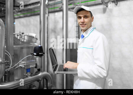 Techniker mit einem Laptop in der Hand an der Milchfabrik Stockfoto