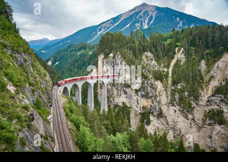 Rote Bahn fährt über der Landwasserbrücke, im Kanton Graubünden, Schweiz. BERNINA Express / Glacier Express verwendet diese Eisenbahn. Stockfoto