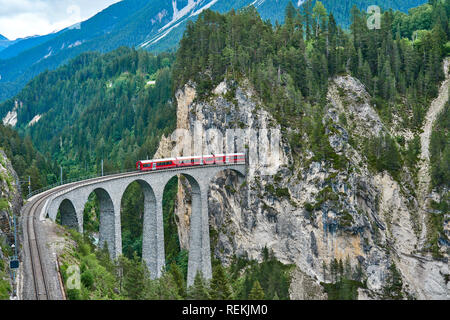 Rote Bahn fährt über der Landwasserbrücke, im Kanton Graubünden, Schweiz. BERNINA Express / Glacier Express verwendet diese Eisenbahn. Stockfoto