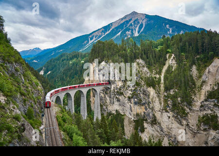 Rote Bahn fährt über der Landwasserbrücke, im Kanton Graubünden, Schweiz. BERNINA Express / Glacier Express verwendet diese Eisenbahn. Stockfoto