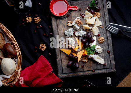 Käseplatte mit Trauben, Honig und Nüssen auf einer hölzernen Hintergrund. Verschiedene Arten von Käse Stockfoto