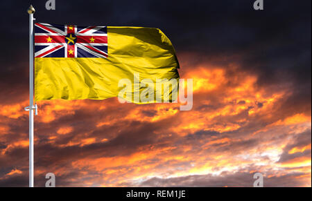 Flagge von Niue am Fahnenmast im Wind flattern gegen einen farbenprächtigen Sonnenuntergang Himmel. Stockfoto