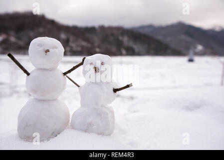 Zwei echte winzig kleine Schneemann in der Natur in verschneiten, kalten Tag in den Bergen. Konzept der schönen Winter und Kinder oder Familie Spaß im Urlaub. Frohe Stockfoto