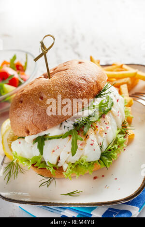 Nahaufnahme eines leckeren Fisch Burger auf Platte mit Pommes frites und Gemüse Salat serviert. Stockfoto