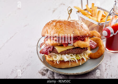 Nahaufnahme eines leckeren Hamburger mit Zwiebelringen und salzige Pommes frites auf einem weißen Holztisch mit Kopie Raum serviert. Stockfoto