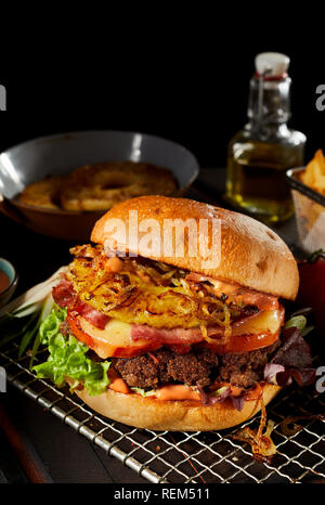 Leckere gegrillte Burger Hawaii mit Ananas, Käse und Schinken auf ein saftiges Rindfleisch Patty, stehend auf einem Gitter in einer Küche Stockfoto