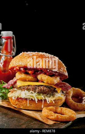 Surf and Turf Spezialität Burger mit goldenen frittierte Tintenfischringe, Rindfleisch Patty und knusprigem Speck überbacken mit geschmolzenem Käse und Grüns auf einem getoasteten Burgerbrötchen Stockfoto