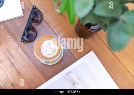 Blick von oben auf die Tasse heiße Milch Kaffee mit späten Kunst auf Holztisch, Lifestyle Konzept Stockfoto