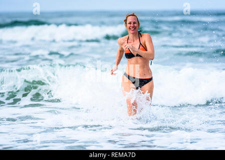 Frau genießen das Meer und die Wellen des Atlantik. Reife, mittlere Alter, junge attraktive Frau im Badeanzug Bikini läuft im Ozean Meer, Verscherzen Stockfoto