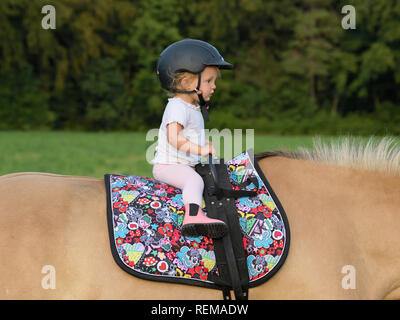 2-jähriges Mädchen sitzt auf einem Pony Stockfoto