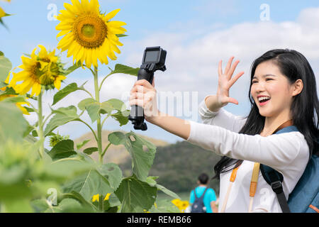 Touristen sind touring das sonnenblumenfeld. Sie gedreht wurde das Video selbst. In einer Art und Weise, haben gelächelt, gut gelaunt. Verwenden selfie Stick als Helfer. Stockfoto