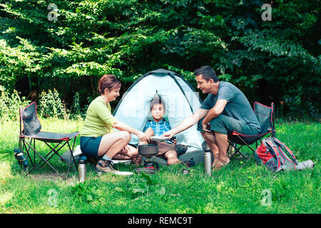 Verbringt einen Urlaub auf dem Campingplatz. Vorbereitung einer Mahlzeit im Freien neben Zelt Stockfoto