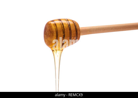 Honig tropft vom Pendelarm auf isolierten weißen Hintergrund. Stockfoto