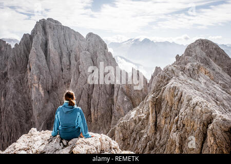 Ansicht von hinten von einem Mädchen, das auf der Spitze eines Berges Stockfoto