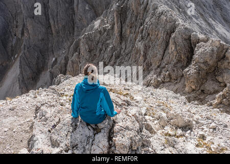 Ansicht von hinten von einem Mädchen, das auf der Spitze eines Berges Stockfoto