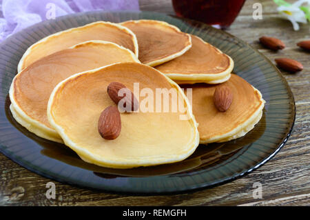 Köstliche Mandel Pfannkuchen mit Kaffee und Marmelade auf einem Holztisch. Nahaufnahme Stockfoto