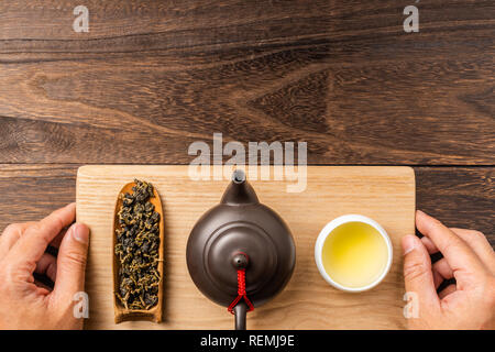 Asien Kultur und Design Konzept-man's Hand halten frische Taiwan oolong Tee und Teekanne auf dunklen Hintergrund Stockfoto