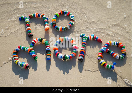 Keine weitere Nachricht von bunten verwendete Kunststoff Flasche Müll auf dem glatten Sand Ufer von einem tropischen Strand Stockfoto