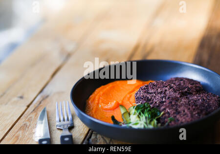 Vegan schwarzer Reis Schnitzel serviert mit orange Karotten mesh und microgreeens. Vegetarische Nahrung hipster Cafe. Platz für Text Stockfoto