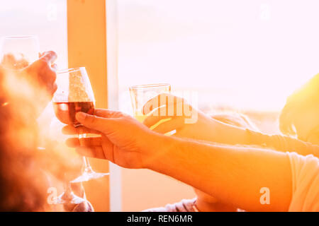 Nahaufnahme der Gläser Jubel und Toasten zusammen mit Wein und Getränke - Gruppe von Menschen, die in der Freundschaft bei Sonnenuntergang Zeit feiern - orange Styl Stockfoto
