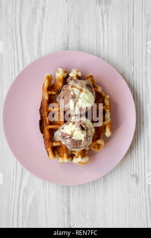 Traditionelle belgische Waffeln mit Eis auf Rosa die Platte über der weißen Holz- Oberfläche, Ansicht von oben. Close-up. Stockfoto