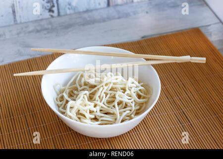 Eiernudeln in weiße Schüssel mit hölzernen Eßstäbchen Stockfoto