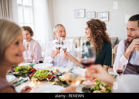 Eine große Familie an einem Tisch sitzen auf einem Indoor Party, anstoßen. Stockfoto