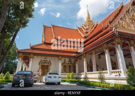 Vientiane, Laos - August 8, 2018: Wat, Foon (phoun), einem buddhistischen Tempel, zwei geparkte Autos, große Bäume und blauer Himmel. Stockfoto