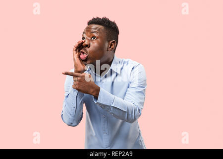 Geheimnis, Klatsch-Konzept. Jungen afro Mann flüsternd ein Geheimnis hinter seiner Hand. Geschäftsmann auf trendy Pink Studio Hintergrund isoliert. Junge Mensch. Menschliche Gefühle, Mimik Konzept. Stockfoto