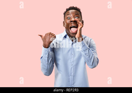 Geheimnis, Klatsch-Konzept. Jungen afro Mann flüsternd ein Geheimnis hinter seiner Hand. Geschäftsmann auf trendy Pink Studio Hintergrund isoliert. Junge Mensch. Menschliche Gefühle, Mimik Konzept. Stockfoto