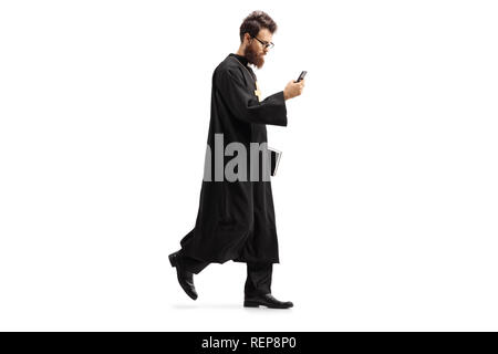 Volle Länge Schuß eines Priesters zu Fuß mit einem Mobiltelefon auf weißem Hintergrund Stockfoto