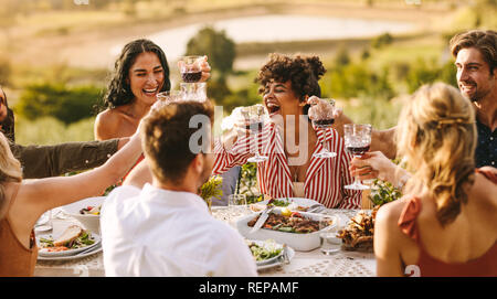 Gruppe von Fröhlichen Freunden in Wein zum Abendessen. Multi-ethnischen Menschen haben eines gemeinsam im Freien. Stockfoto