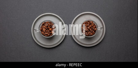 Kaffeebohnen in zwei Glas Tassen mit sausers, auf Schwarz Farbe Hintergrund, Ansicht von oben Stockfoto