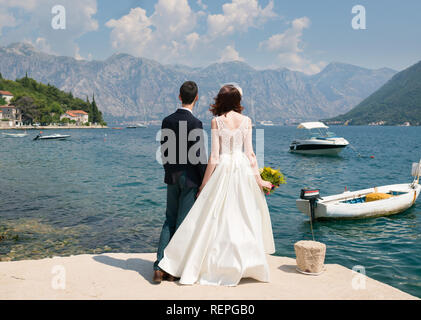 Brautpaar stand auf dem Pier und Blick auf das Meer, Hände halten Stockfoto