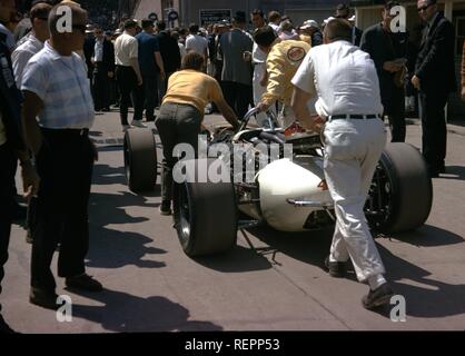 Gruppe von Männern Schieben eines Rennwagens durch eine Masse von Menschen in die Grube nach einem Rennen, Indiana, 1968. () Stockfoto